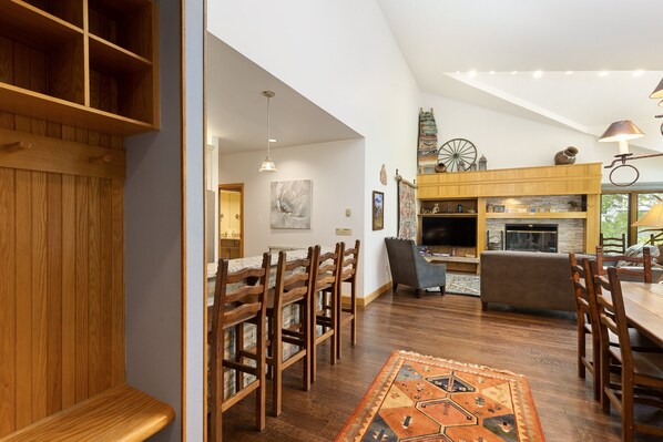 Un vaste espace de vie comprenant une table à manger en bois, des chaises, un canapé et une cheminée.