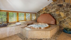 A bathroom with a stone wall, a wooden bench, and a bathtub. - 2708 Chateaux Dmont 3 Bedroom Condo (Keystone)