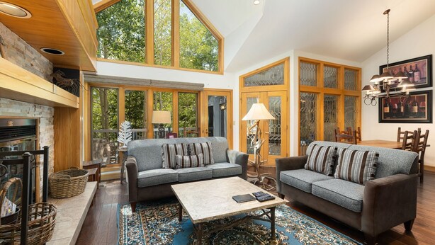A spacious living room with two sofas, a coffee table, and a fireplace. Large windows provide natural light and views of the outdoors. - 2708 Chateaux Dmont 3 Bedroom Condo (Keystone)