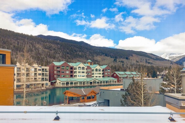 A hotel with multiple buildings, a river, and mountains in the background. - The Mall 1429 1 Bedroom Condo (Keystone)