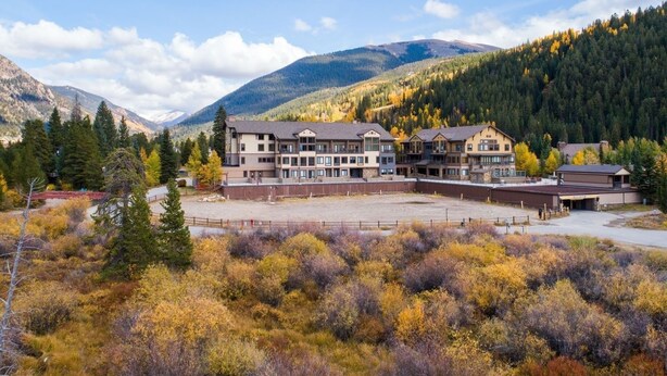 A multi-story hotel with a large parking area, surrounded by autumn foliage and mountains. - 2797 Slopeside Condo (Keystone)