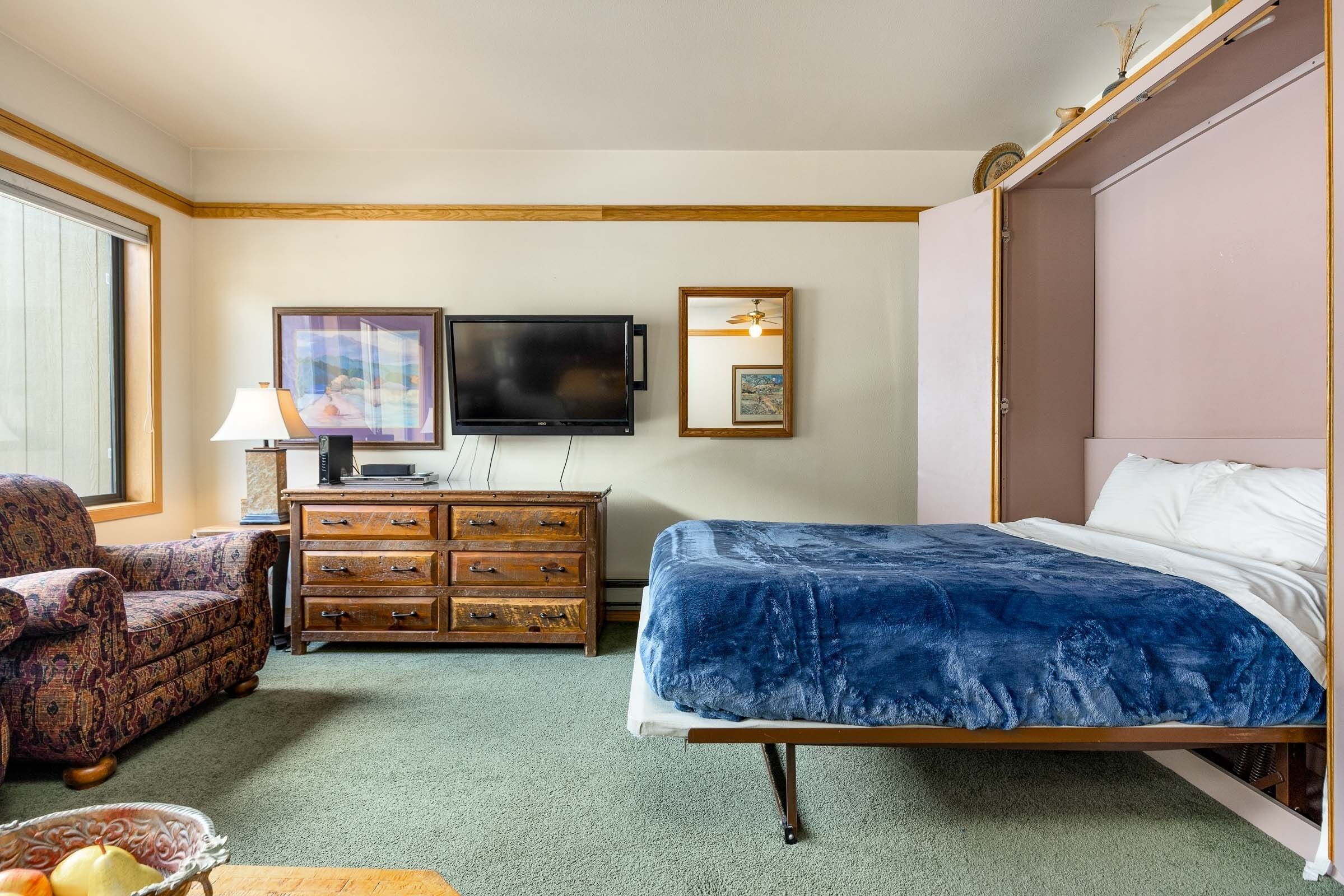 Une chambre d’hôtel avec un lit, une télévision, une commode, une chaise et une fenêtre.