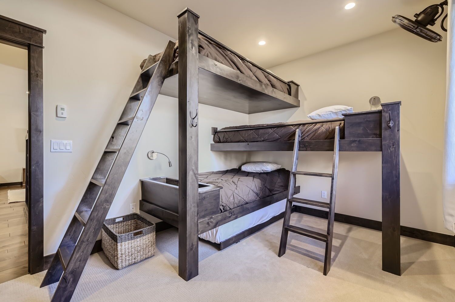 A bunk bed room with a ladder, a small sink, and a basket.