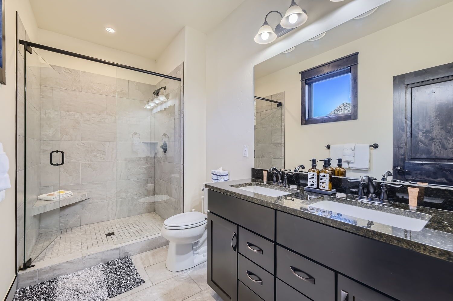 A modern bathroom with a glass-enclosed shower, a vanity with dual sinks, and a large mirror.