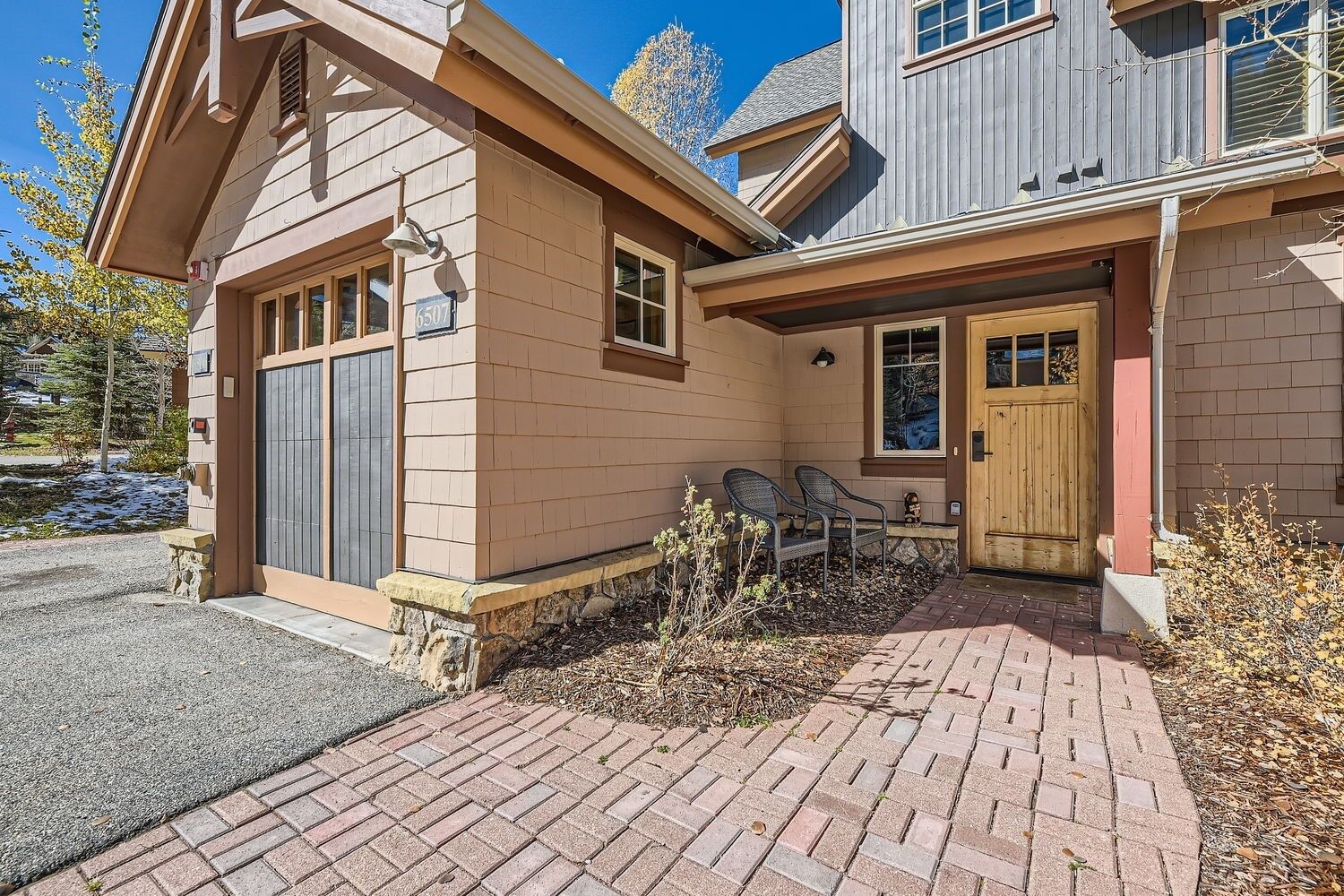 A two-story house with a brick driveway and a covered porch area.