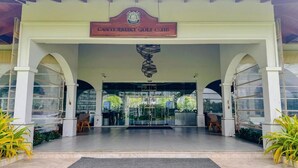 A entrada do Canterbury Golf Club, com uma placa acima das portas, uma escultura espiral e plantas em vasos.