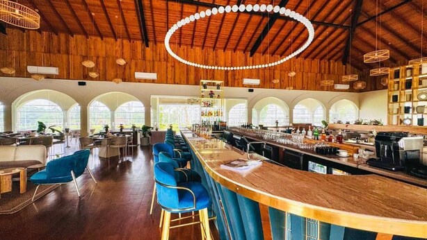 Um espaço amplo para bar com tetos altos de madeira, diversas opções de assento e ambiente bem iluminado.