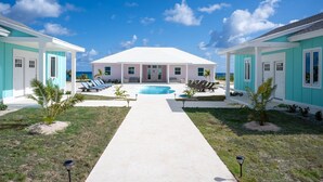 A two-story house with a swimming pool, a covered patio, and a view of the ocean. - Pink Sands Point Main House 4 Bedroom Home (Governor's Harbour)