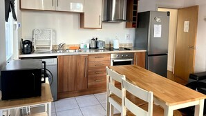 A compact kitchen with wooden cabinets, a built-in oven, a sink, and a dining table with chairs. - Bright 1 bedroom flat, balcony, 8 min to London Bridge (London)