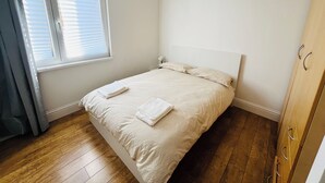 A bedroom with a bed, a window with blinds, a wooden floor, and a wardrobe. - Bright 1 bedroom flat, balcony, 8 min to London Bridge (London)
