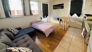 A compact living space with a sofa, a bed, a dining table with chairs, and a kitchen area. - Bright 1 bedroom flat, balcony, 8 min to London Bridge (London)