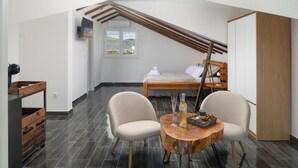 Ein modernes Schlafzimmer mit schrägverdeckter Decke, einem Bett, einem hölzernen Kleiderschrank und einem runden Holztisch mit Stühlen.