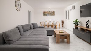 Ein modernes Wohnzimmer mit einem grauen Ecksofa, einem Holztisch und einem Fernseher auf einem Schrank.