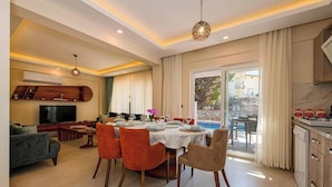 A modern living room with a dining area, a TV, and a kitchen. - Close to Oludeniz 5 Bedroom Villa (Fethiye)