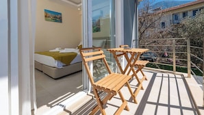 A balcony with wooden chairs and a table, a bed with a yellow blanket, and a painting of a bridge on the wall. - Close to Oludeniz 5 Bedroom Villa (Fethiye)