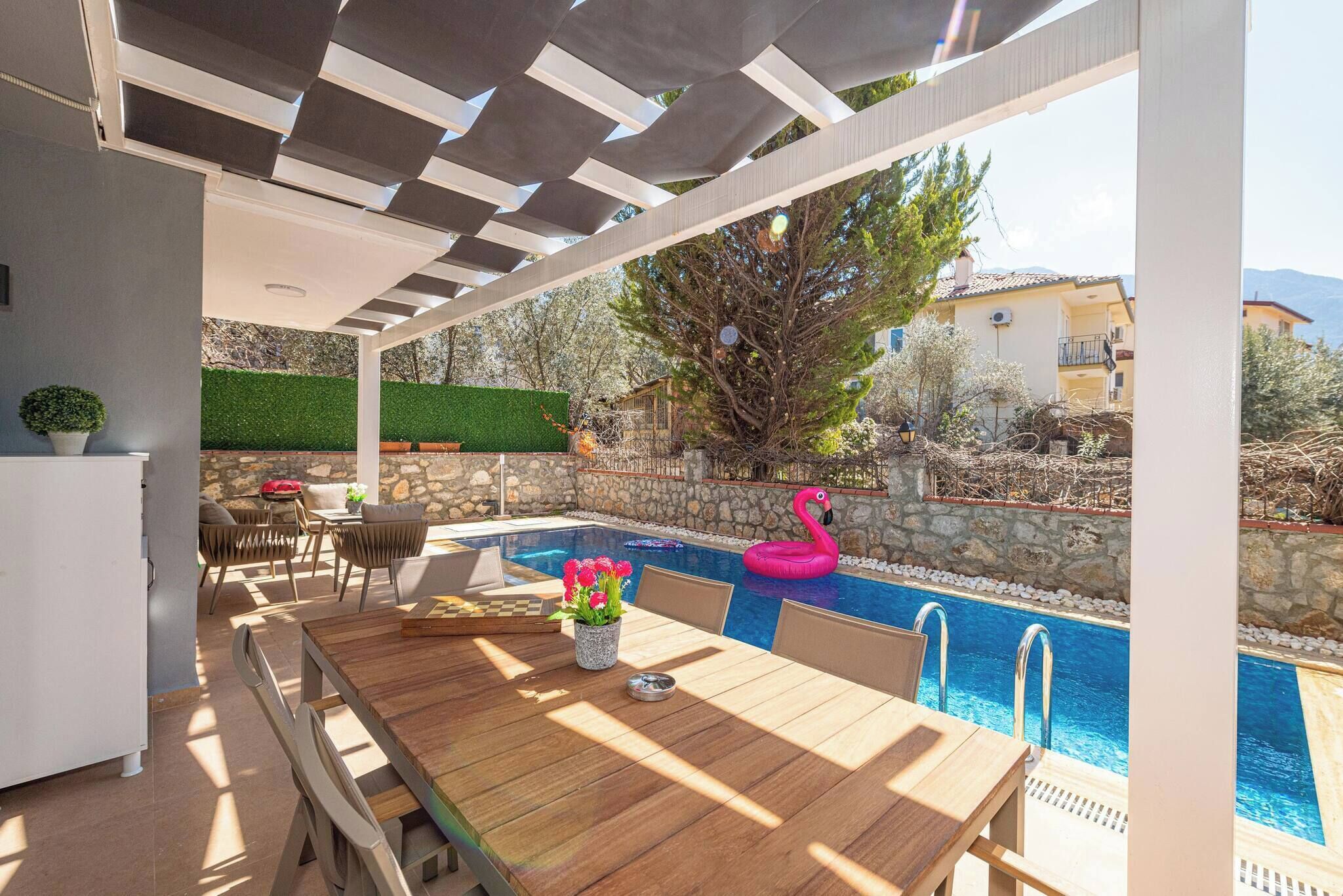 Un patio exterior con piscina, mobiliario de madera y un flotador con forma de flamenco.