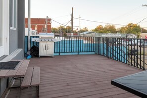 A wooden deck with a barbecue grill, a pool, and a fenced area.