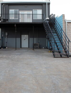 A building with a staircase leading to a balcony, a door, and a sign on the wall.