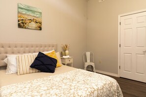 A bedroom with a bed, a nightstand, a chair, and a door.