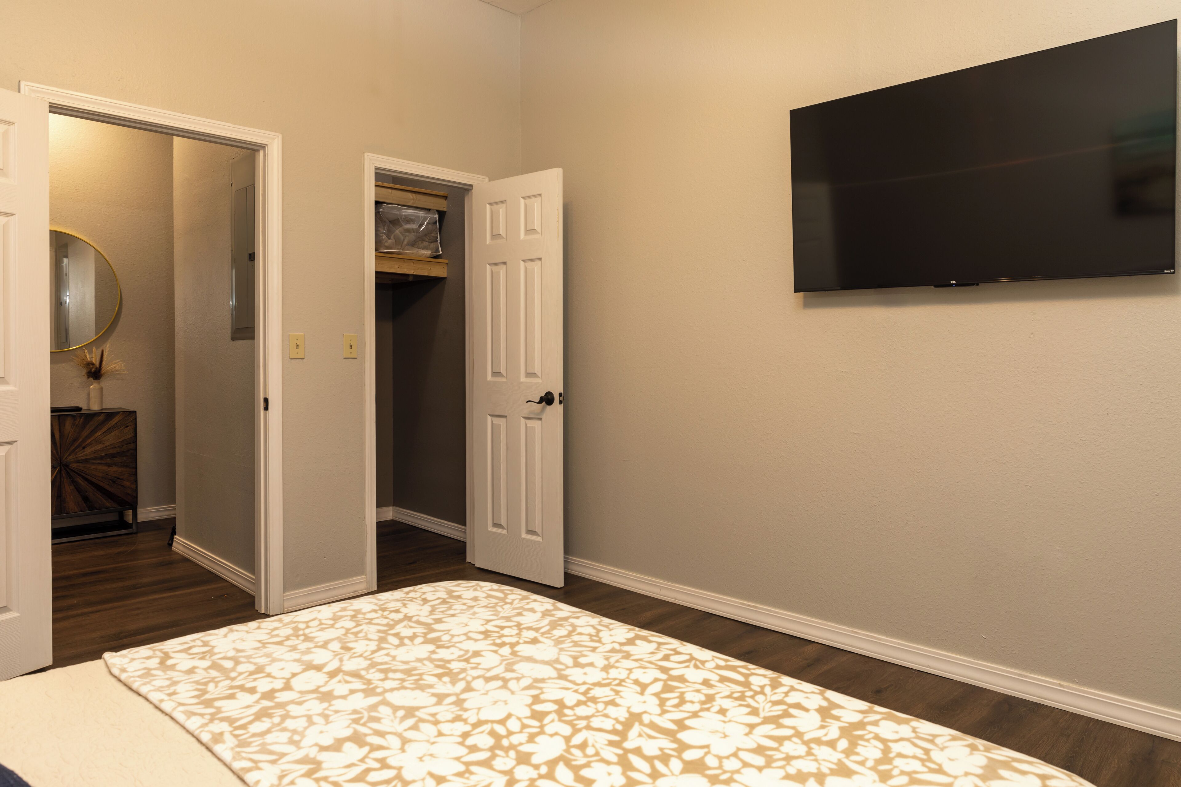 A bedroom with a bed, a television mounted on the wall, and a door leading to a closet.