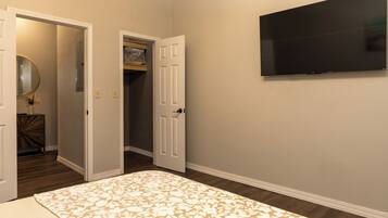 A bedroom with a bed, a television mounted on the wall, and a door leading to a closet.