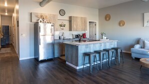 A modern kitchen with a central island, stainless steel appliances, and a bar stool seating area.