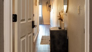 A hallway with a wooden floor, white walls, and a black console table with a vase.