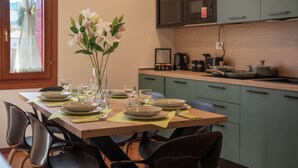 A dining table set with plates, glasses, and cutlery, surrounded by chairs.
