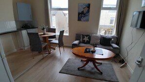 Un espacio habitable compacto con zona de comedor, sofá y televisor.