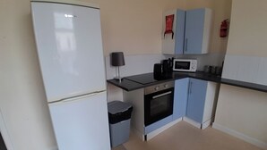 Cocina compacta con refrigerador, microondas, estufa y armarios.