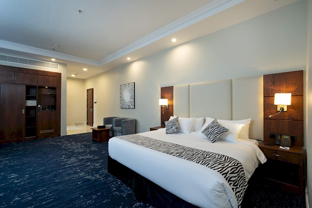 Habitación de hotel con una cama grande, un escritorio, una silla, un armario y un cuadro en la pared.