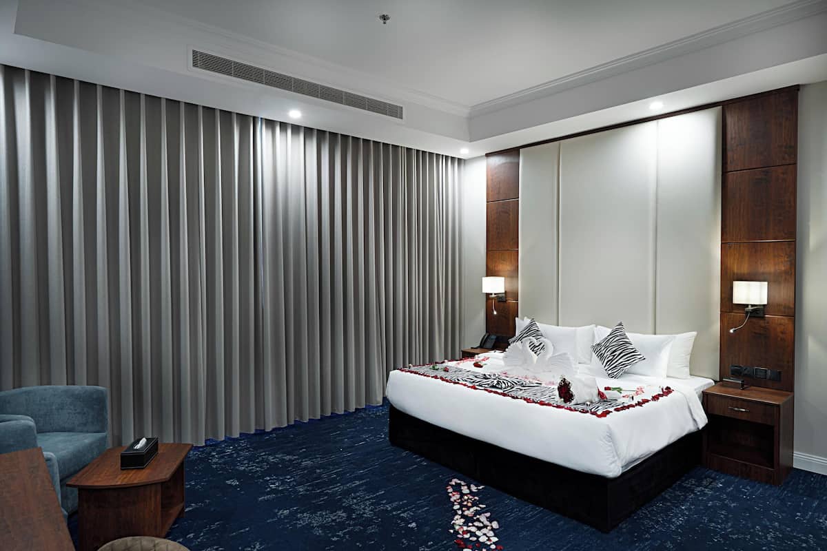 Una habitación de hotel con una cama grande, un escritorio, una silla, un armario y un espejo amplio.