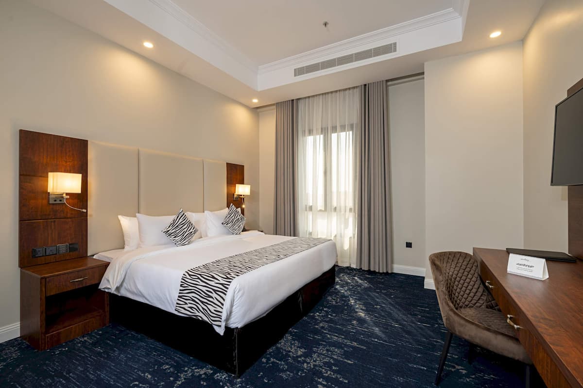 Una habitación de hotel con una cama grande, un escritorio, una silla y un televisor.