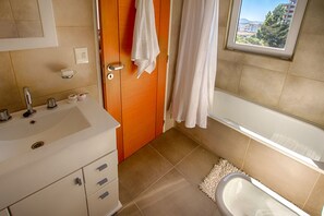 Une salle de bain avec un lavabo, un miroir, une porte en bois et une fenêtre donnant sur un paysage agréable.