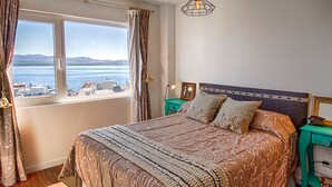 Ein Schlafzimmer mit einem großen Bett, Blick auf das Meer und die Stadt.