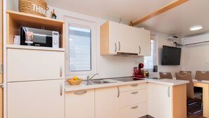 Une cuisine moderne avec des meubles blancs, un four à micro-ondes, un évier et un coin repas avec des chaises.