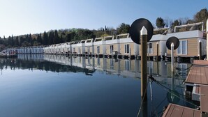 Une rangée de maisons flottantes offrant une vue dégagée sur l’eau et les arbres en arrière-plan.