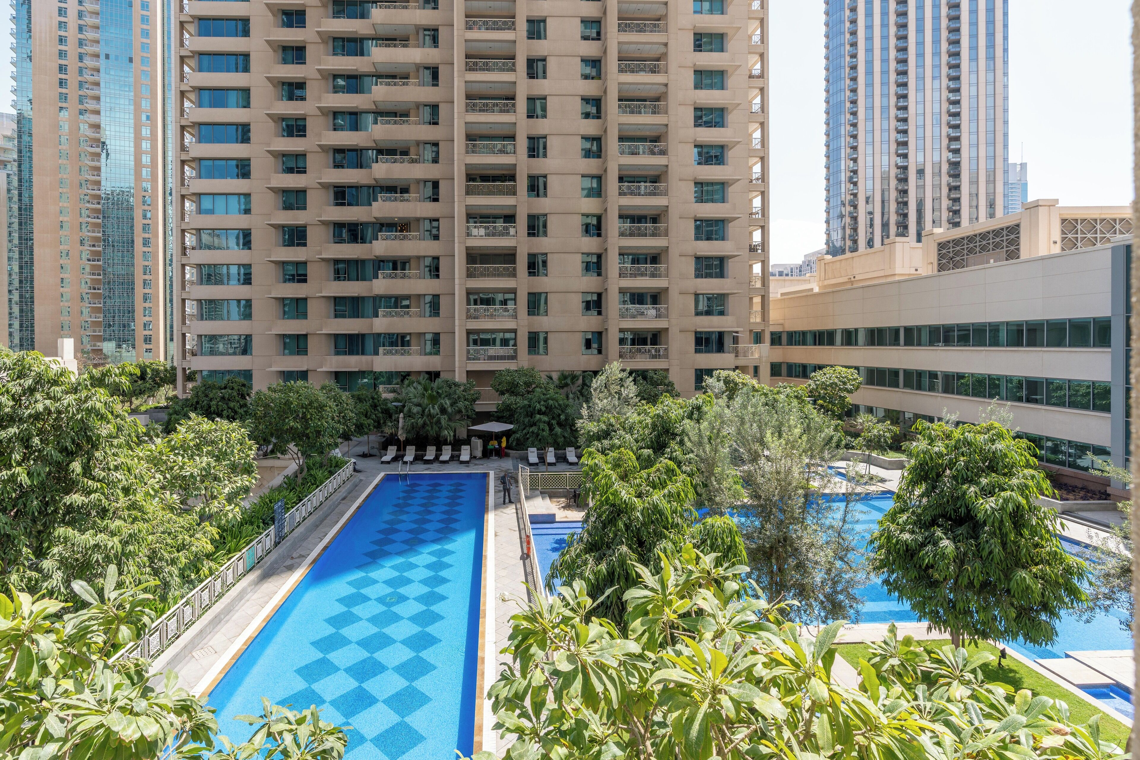 A swimming pool surrounded by lush greenery and tall buildings.
