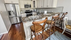 A modern kitchen with white cabinets, stainless steel appliances, and a granite countertop. - New! Large 2 Bedroom Kelleys Island Condo (Kelleys Island)