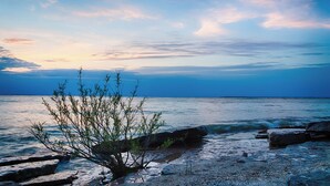 A beach scene with rocky shoreline and sparse vegetation. - New! Large 2 Bedroom Kelleys Island Condo (Kelleys Island)
