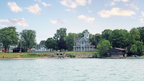 A large waterfront property with a prominent house featuring a wrap-around porch and a tower. - New! Large 2 Bedroom Kelleys Island Condo (Kelleys Island)