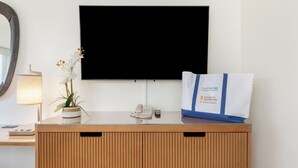 A reception desk with a flat-screen TV, a potted plant, a lamp, a phone, and a bag with a hotel logo. - Ocean Views + Walkway to Mall-Ala Moana Hotel 2513 (Honolulu)