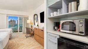 A hotel room with a bed, a dining area with a microwave, coffee maker, and a dishwasher. - Ocean Views + Walkway to Mall-Ala Moana Hotel 2513 (Honolulu)