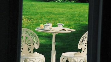 Relax in a serene garden setting with a charming table and chairs, perfect for reading or enjoying a quiet moment.