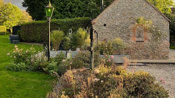 Un bâtiment en pierre à l’architecture traditionnelle, entouré de jardins bien entretenus et sous un ciel dégagé.