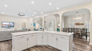 Una cocina amplia con armarios blancos, una isla grande y un comedor con sillas de madera.