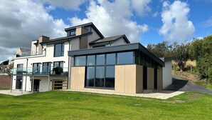 A modern two-story house with large windows, a balcony, and a well-maintained lawn. - Spacious 6-bedroom house with WiFi, AC in enjoyable Dunmore East (Dunmore East)