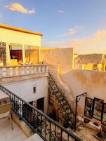 Terraza en la azotea con escalera, mobiliario exterior y vistas de la ciudad.