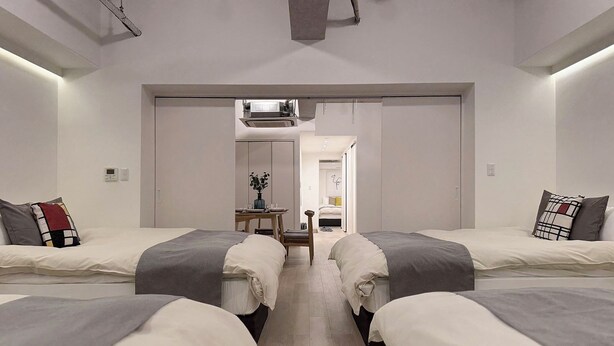 Una habitación de hotel moderna con dos camas, una mesita con un florero y vistas al pasillo.