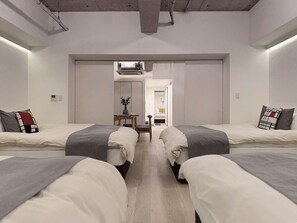 Et moderne hotelværelse med to senge, et lille bord med en vase og udsigt til gangen.